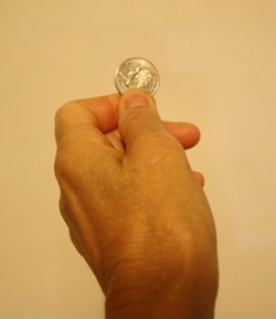 A hand holding a quarter between thumb and forefinger