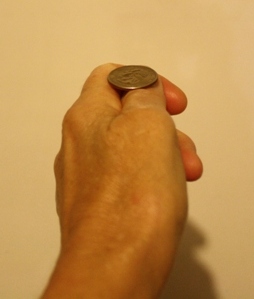 A left hand with a coin on the thumb ready to be tossed